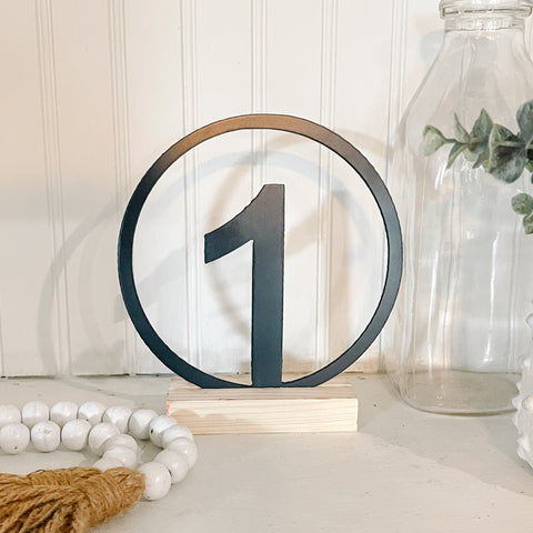 Decorative table number '1' on a wooden stand with a neutral background