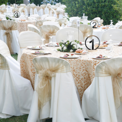 Decorated wedding reception with tables and chairs covered in white and gold tablecloths.