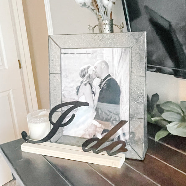Wedding decor used in bedroom setup with a framed photo, candle, and decorative elements on a surface.